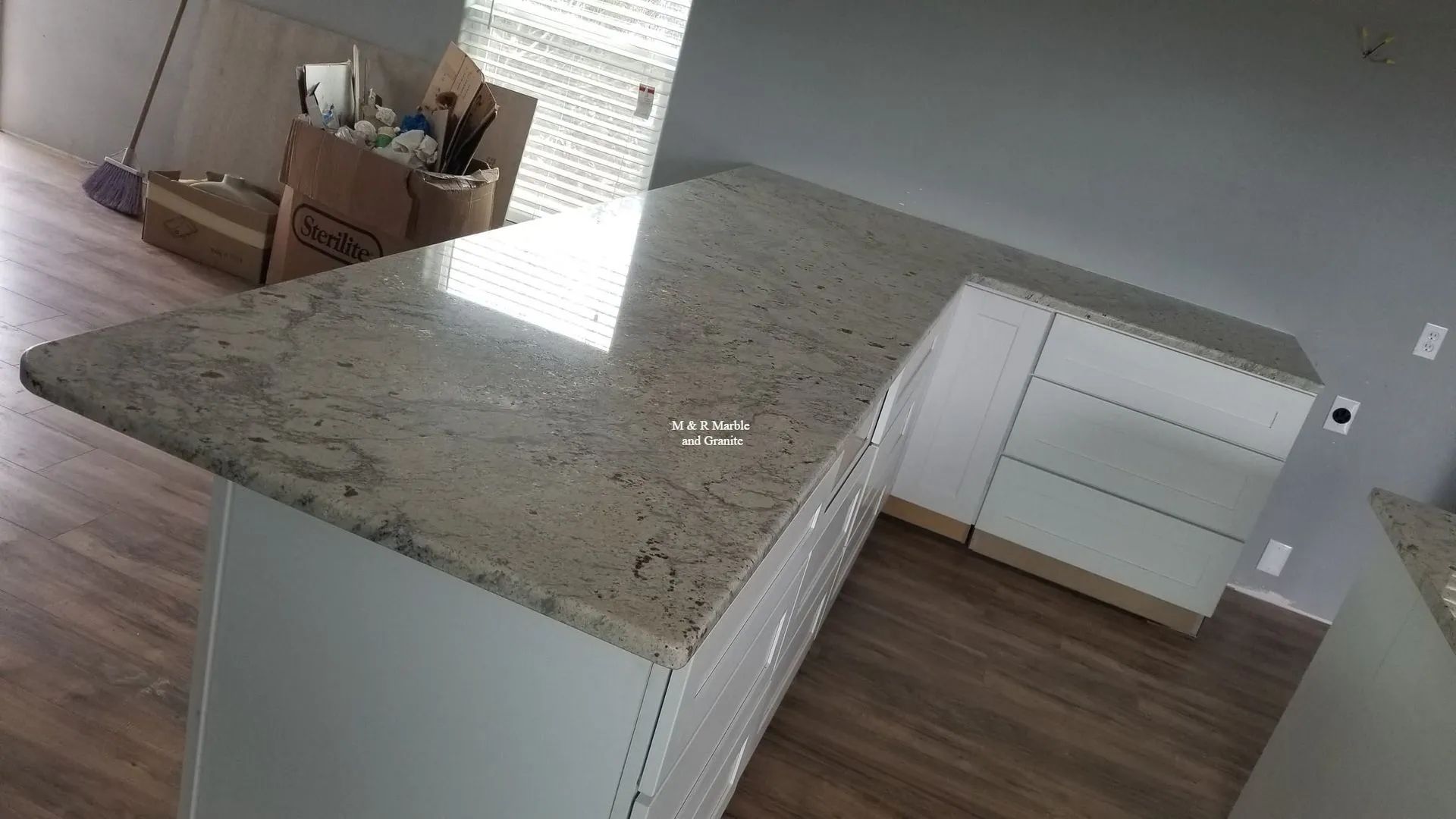 A kitchen with a granite counter top and white cabinets.