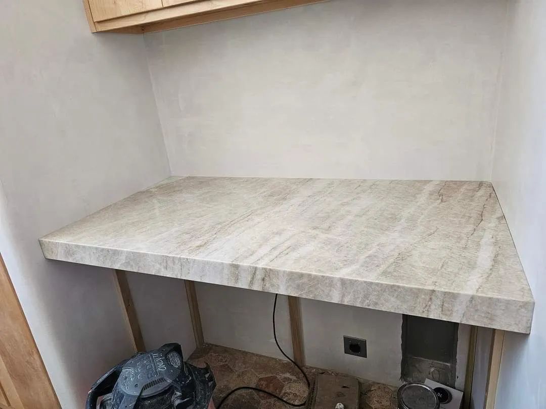 A marble counter top is being built in a corner of a room.