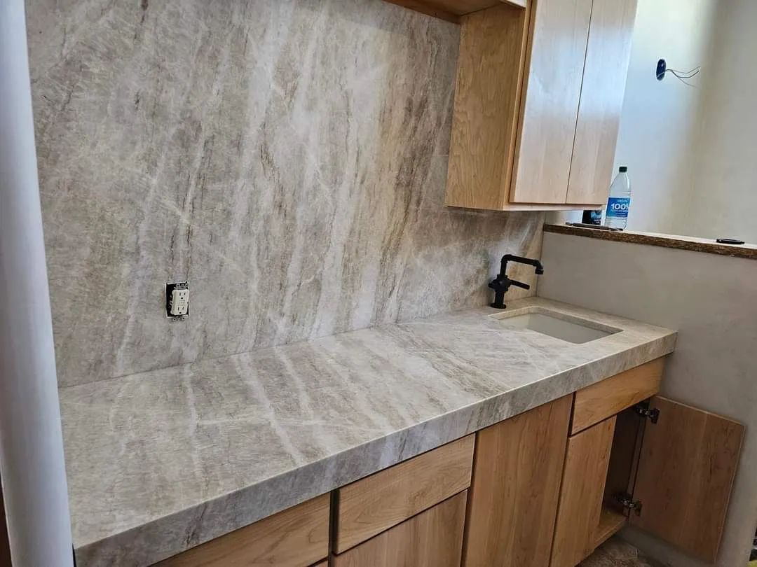 A kitchen with a marble counter top and wooden cabinets.