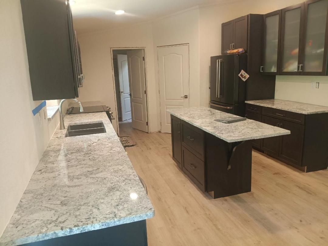 Kitchen with dark brown cabinets, granite countertops, and a light-colored wood floor.