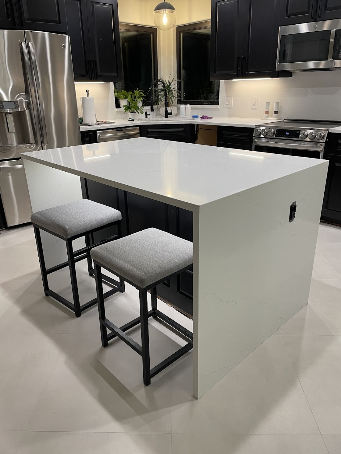 Modern kitchen island with white countertop and two gray stools.