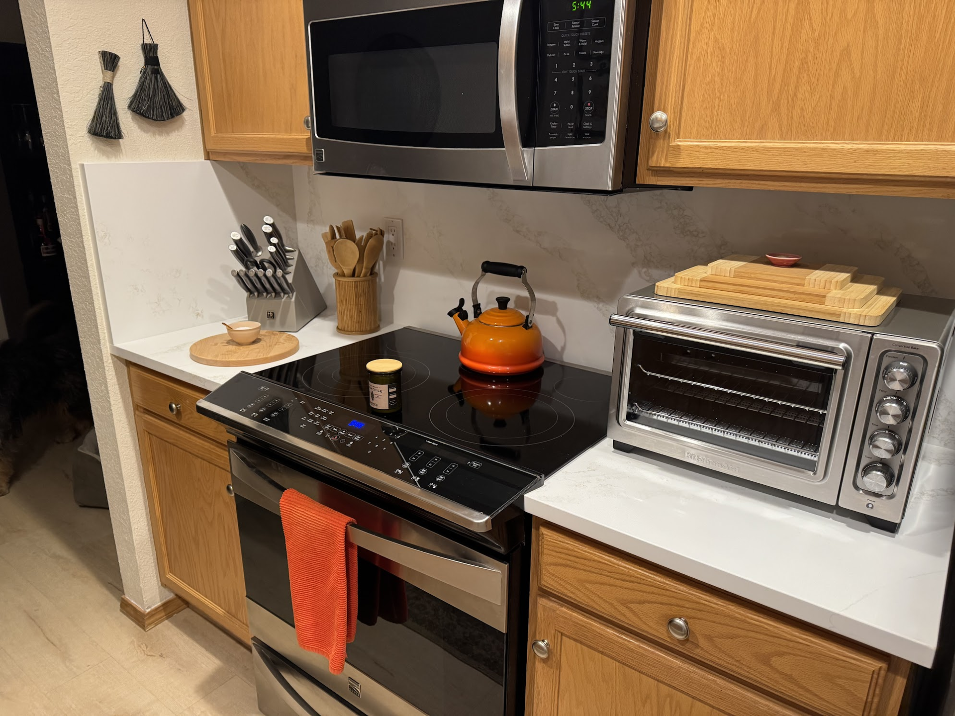 Kitchen with light wood cabinets, stainless steel appliances, and a countertop with a toaster oven and tea kettle.