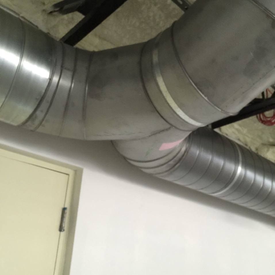 A large metal pipe is hanging from the ceiling in a room.