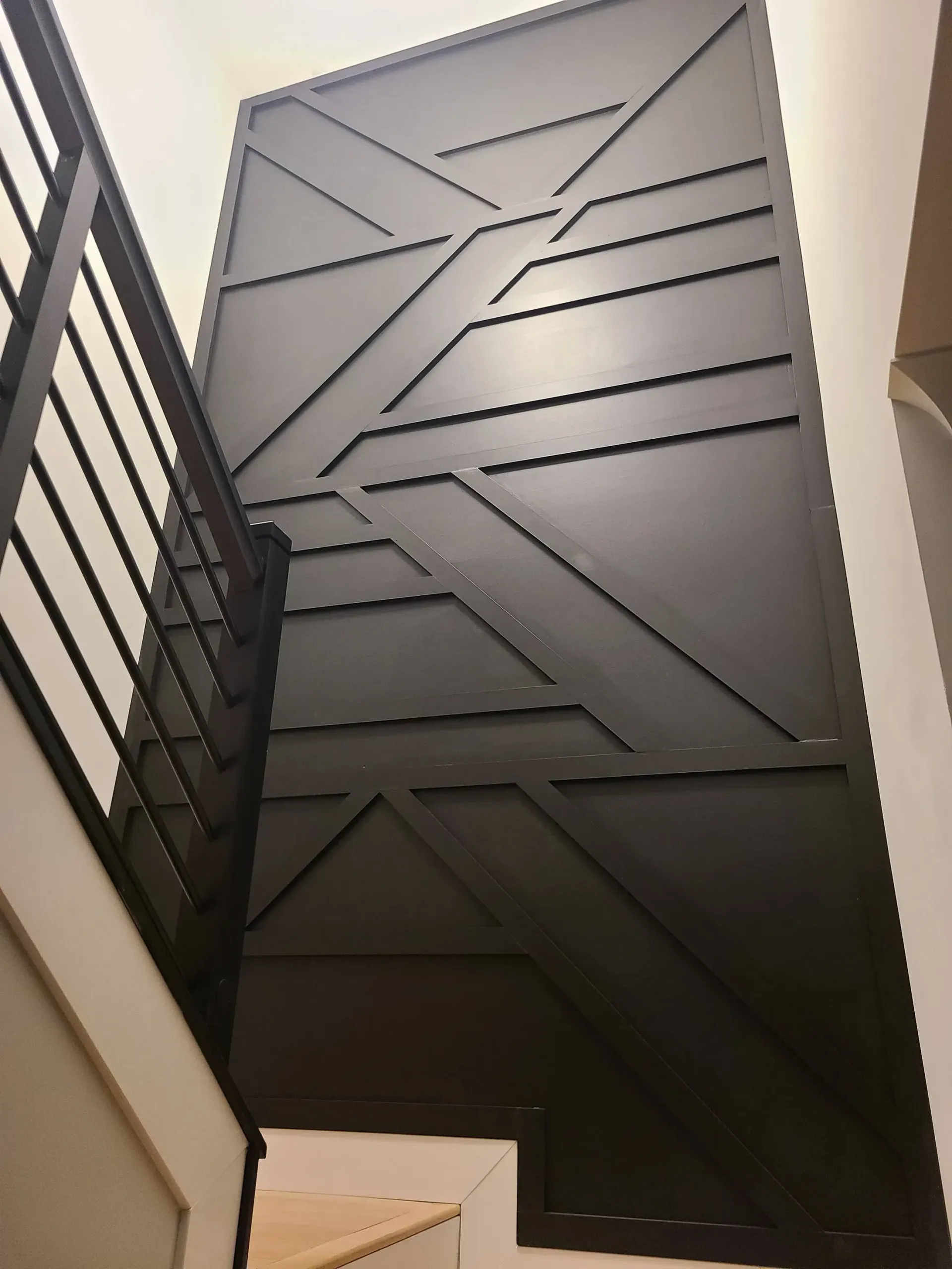Black geometric accent wall with staircase railing.