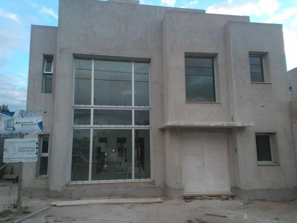 Edificio beige de dos plantas con grandes ventanales frontales y entrada retranqueada, actualmente en construcción.