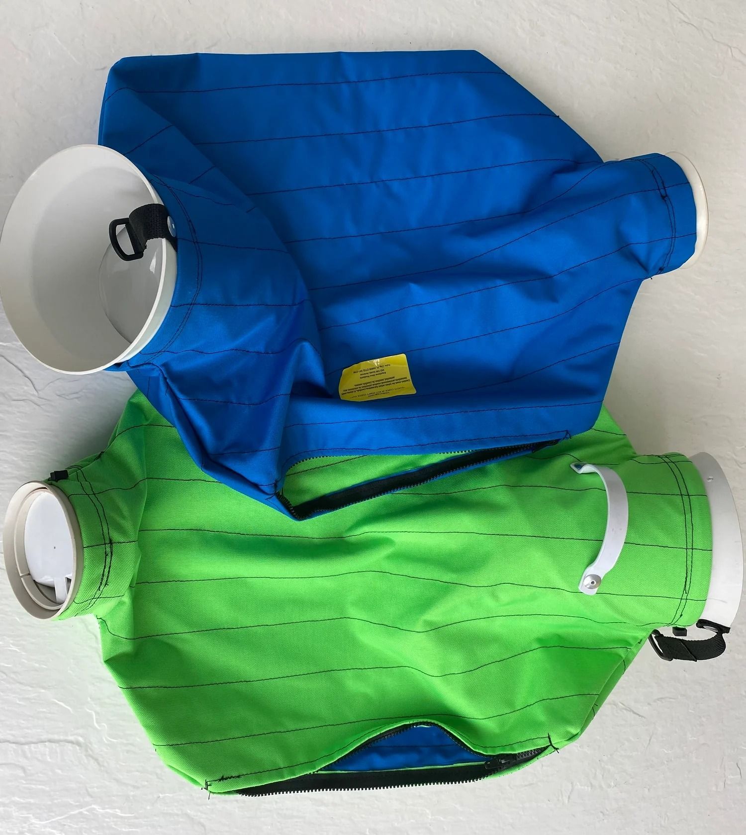 Two fabric air duct covers, blue and green, with white plastic collars.