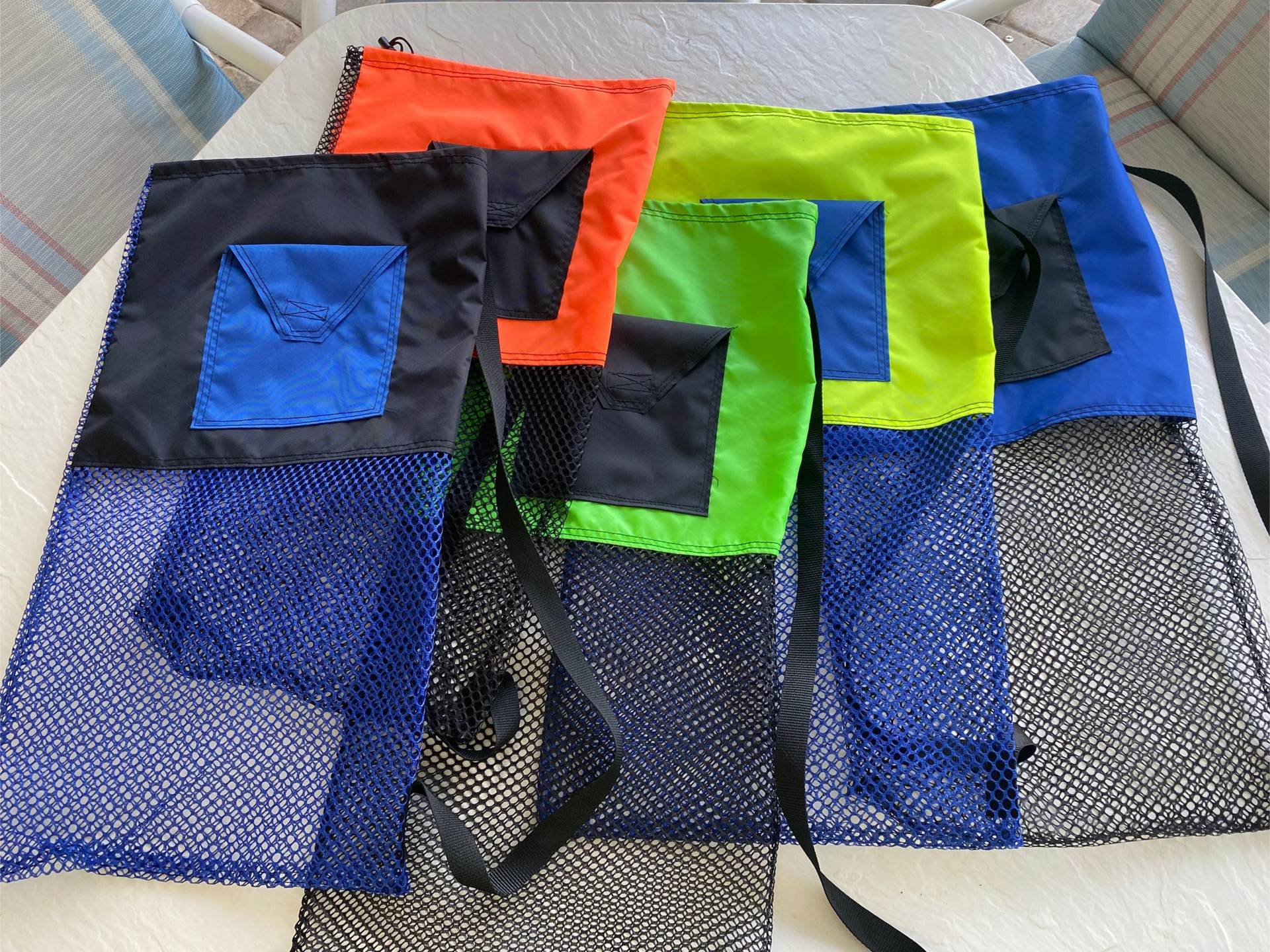 Colorful mesh beach bags with pockets and straps.