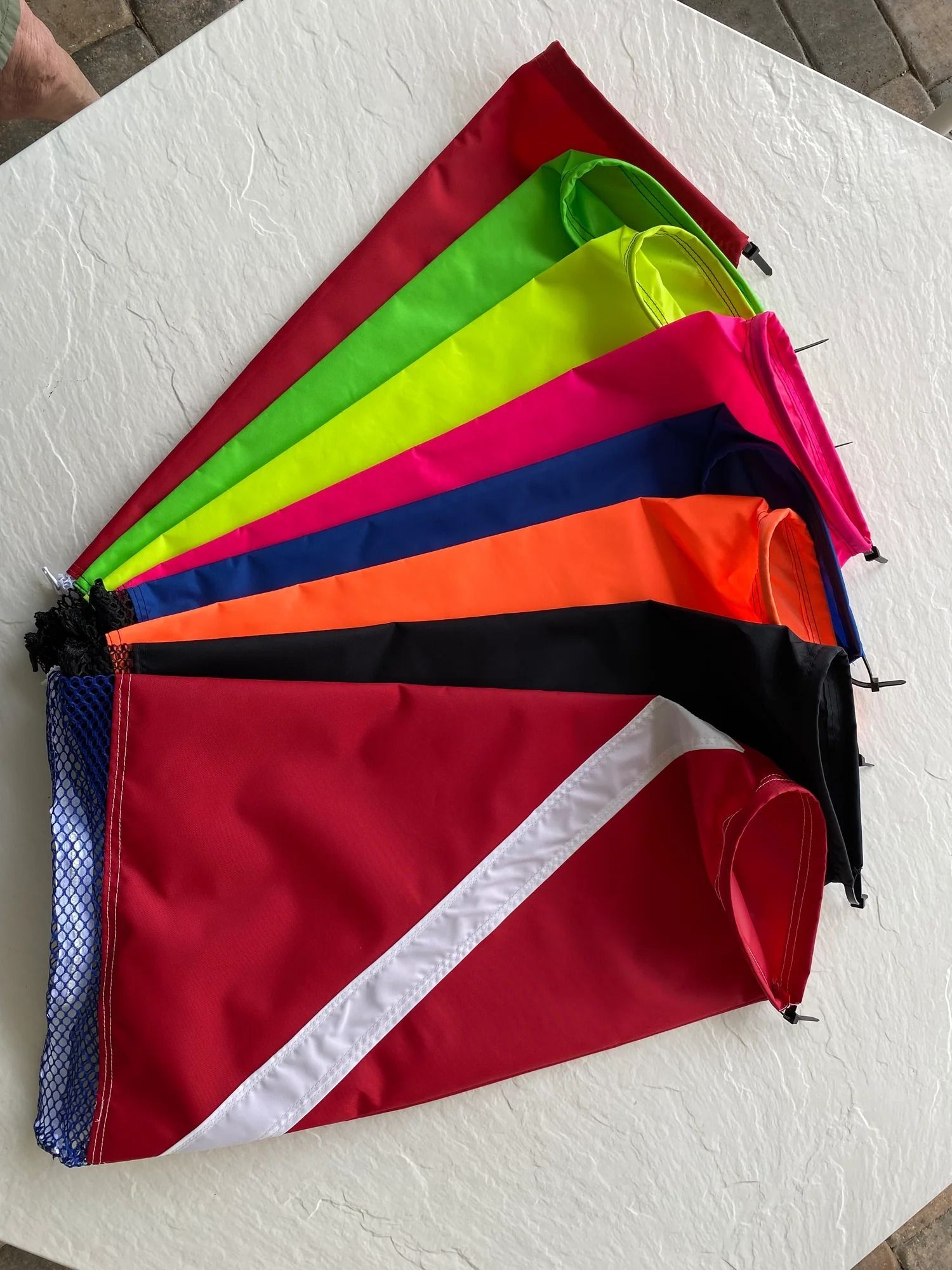 Array of colorful diver-down flags, including red with white diagonal stripe.
