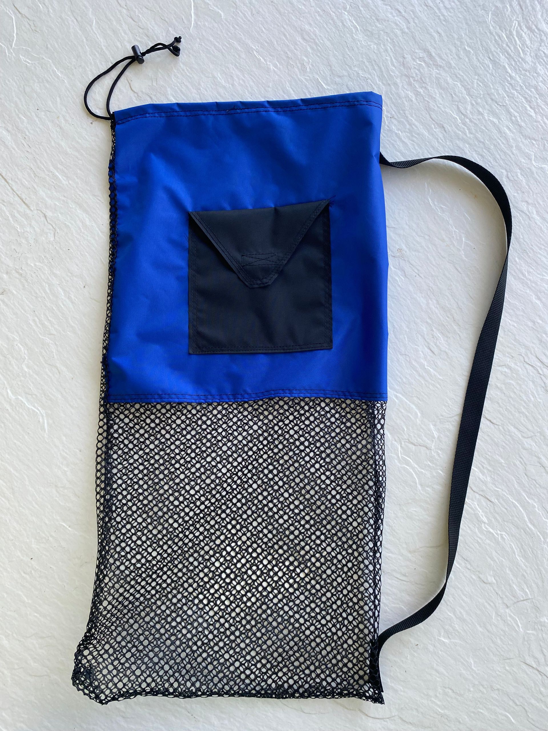 Blue and gray bag with a black pocket and shoulder strap. Drawstring closure at the top.