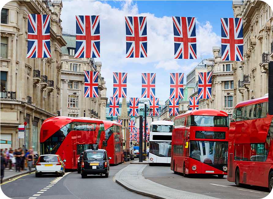 London street scene with red double-decker buses, black cabs, Union Jack flags.