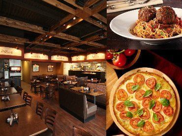 Interior of an Italian restaurant with wooden beams and seating, spaghetti with meatballs, and tomato basil pizza.