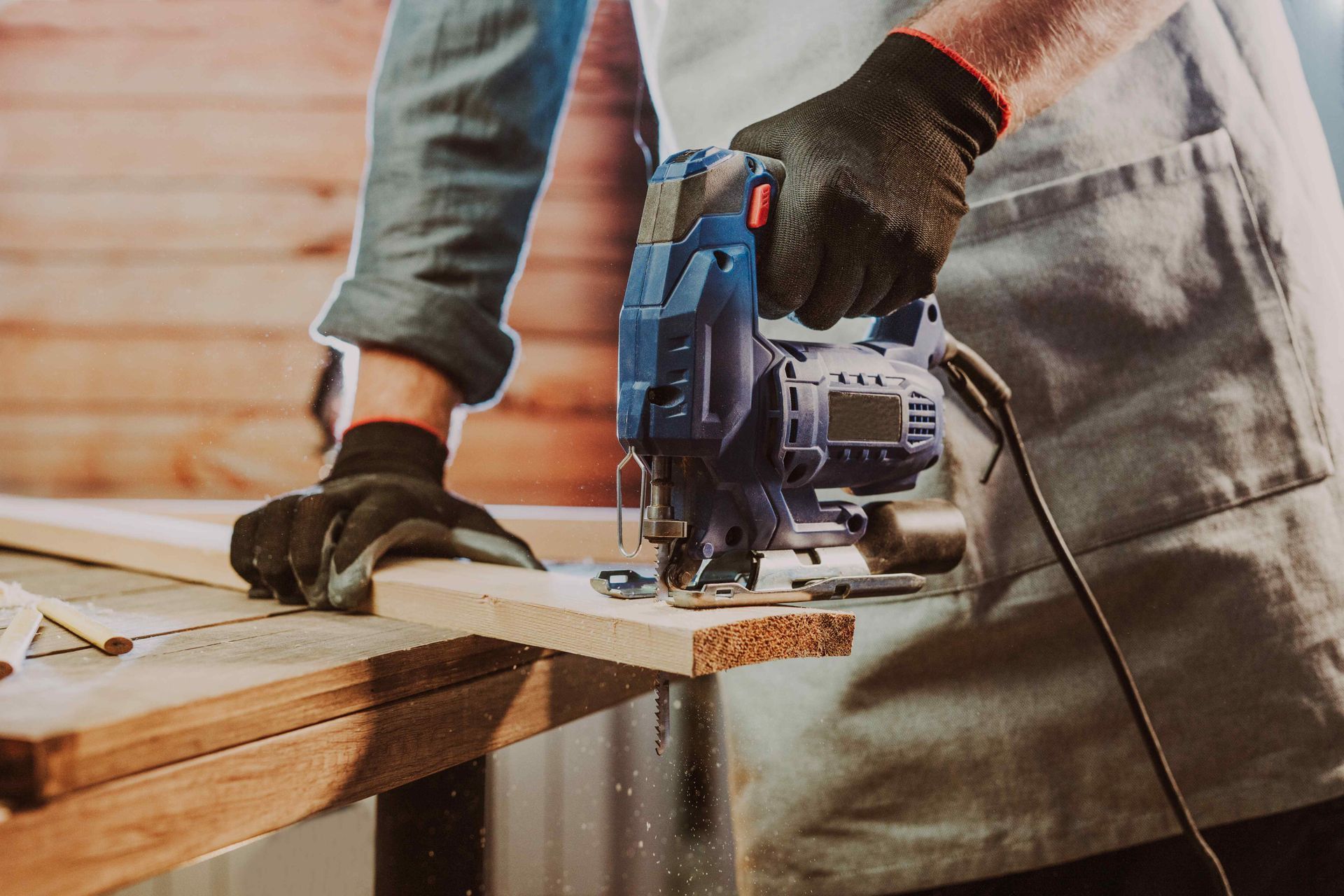 A man is using a jigsaw to cut a piece of wood.