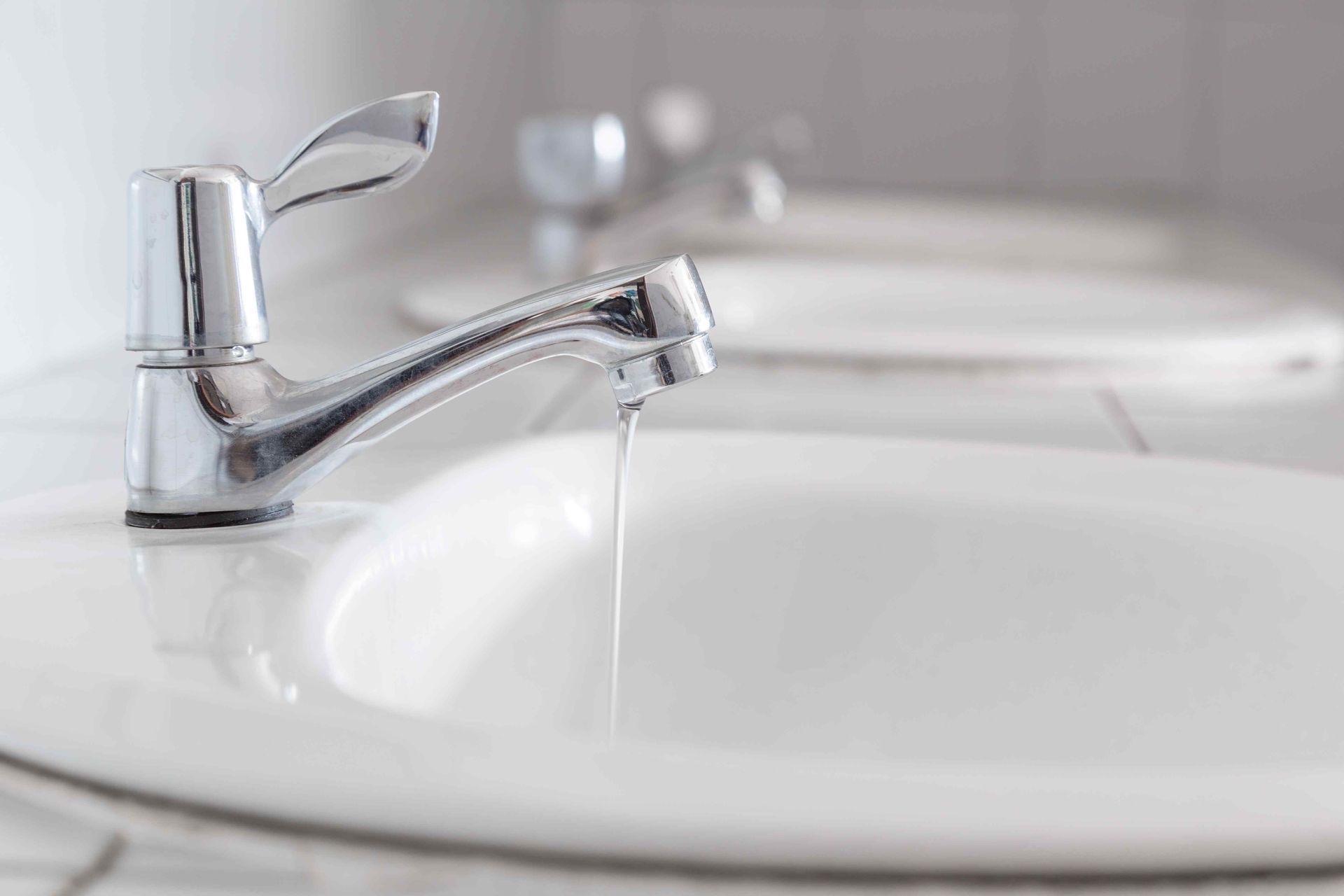 A close up of a bathroom sink with water running from the faucet.