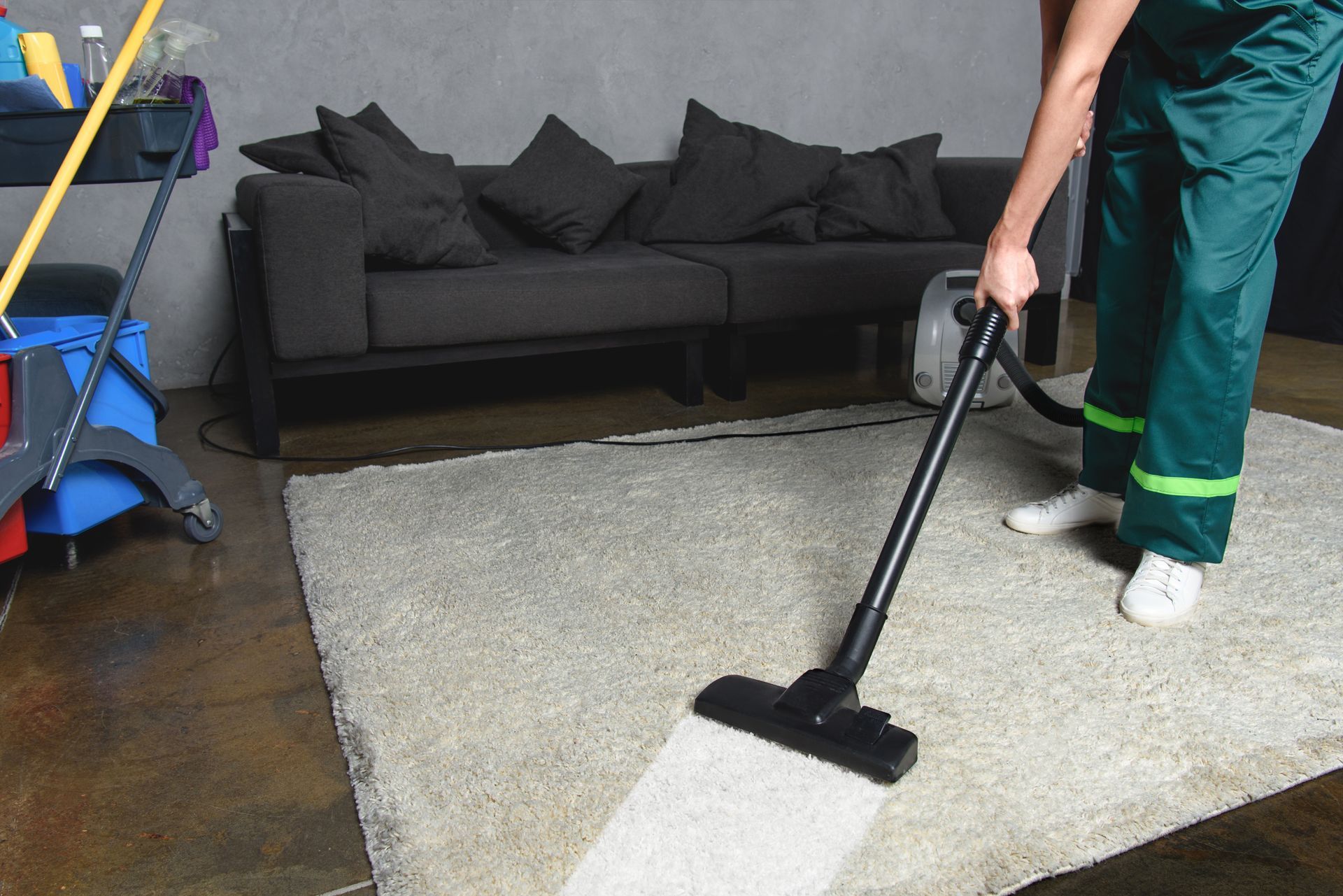 Person using a vacuum cleaner to clean a white carpet, diligently removing dust and debris.