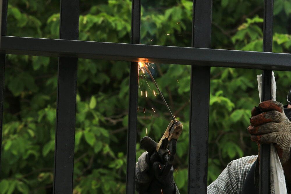 A Person Welding a Black Metal Fence, Sparks Flying — Townsville Stainless Steel in Port Douglas, QLD