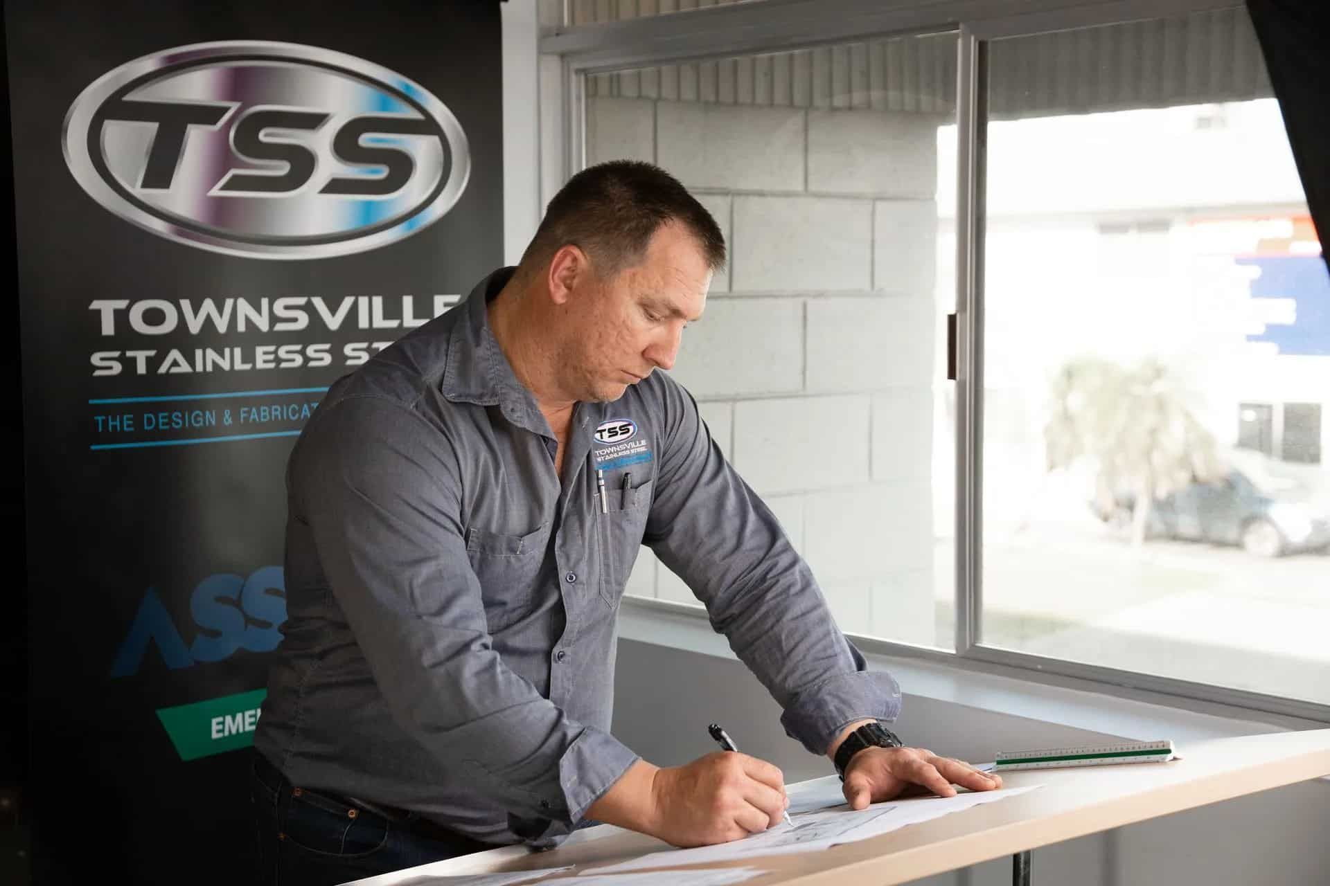 Man in a Grey Shirt Writing on a Paper— Townsville Stainless Steel in Garbutt, QLD