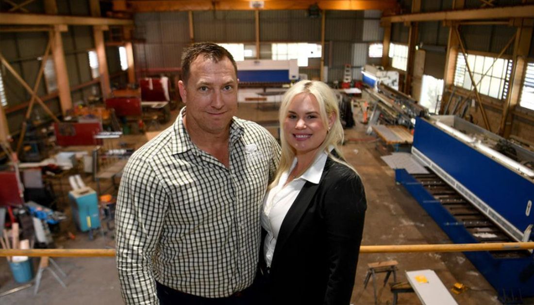 A Man and A Woman Are Posing for A Picture in A Factory — Townsville Stainless Steel in Garbutt, QLD