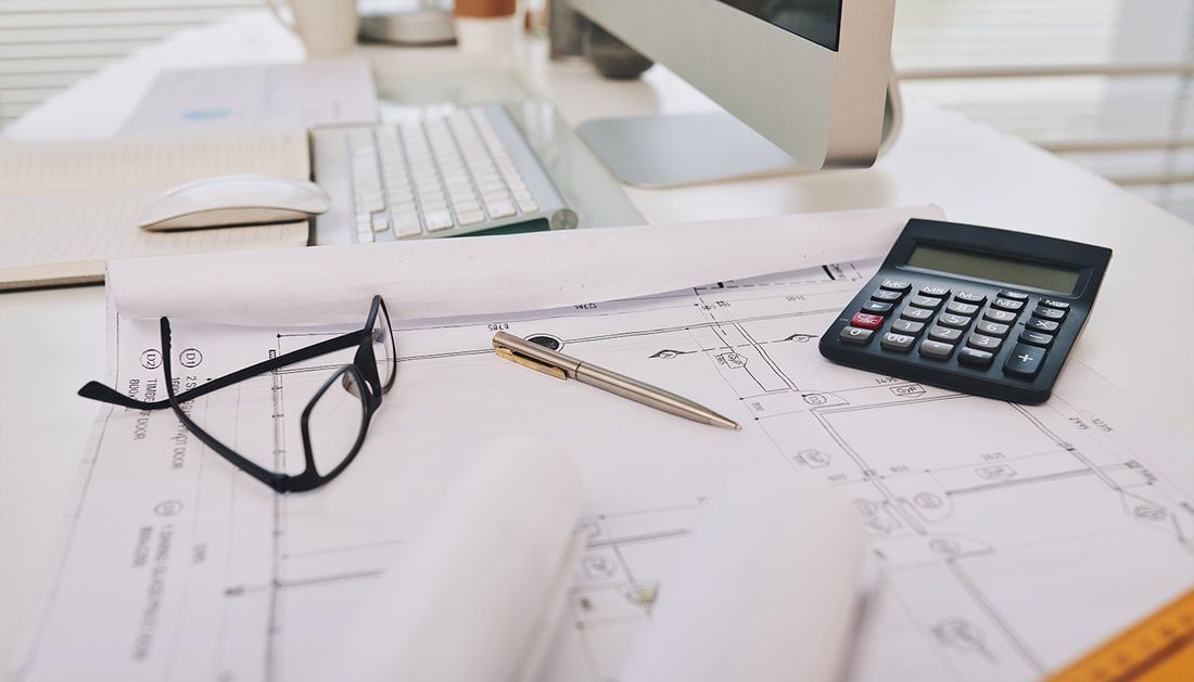 A Desk with A Computer, Calculator, Pen, and Glasses on It — Townsville Stainless Steel in Garbutt, QLD