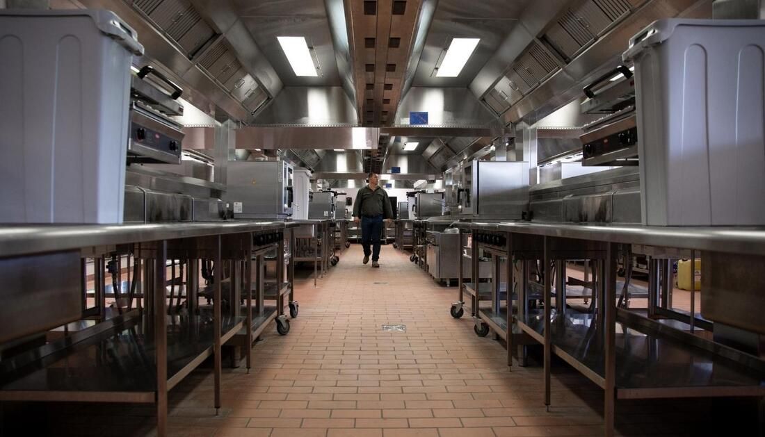 A Person Walks Through a Commercial Kitchen With Stainless Steel Counters — Townsville Stainless Steel in Garbutt, QLD
