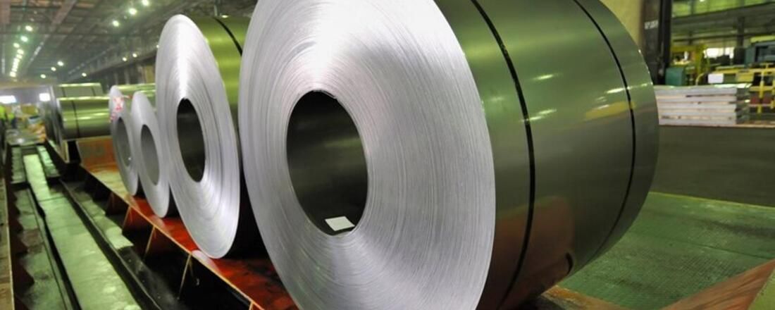 A Bunch of Rolls of Metal Are Sitting on A Conveyor Belt in A Factory — Townsville Stainless Steel in Garbutt, QLD