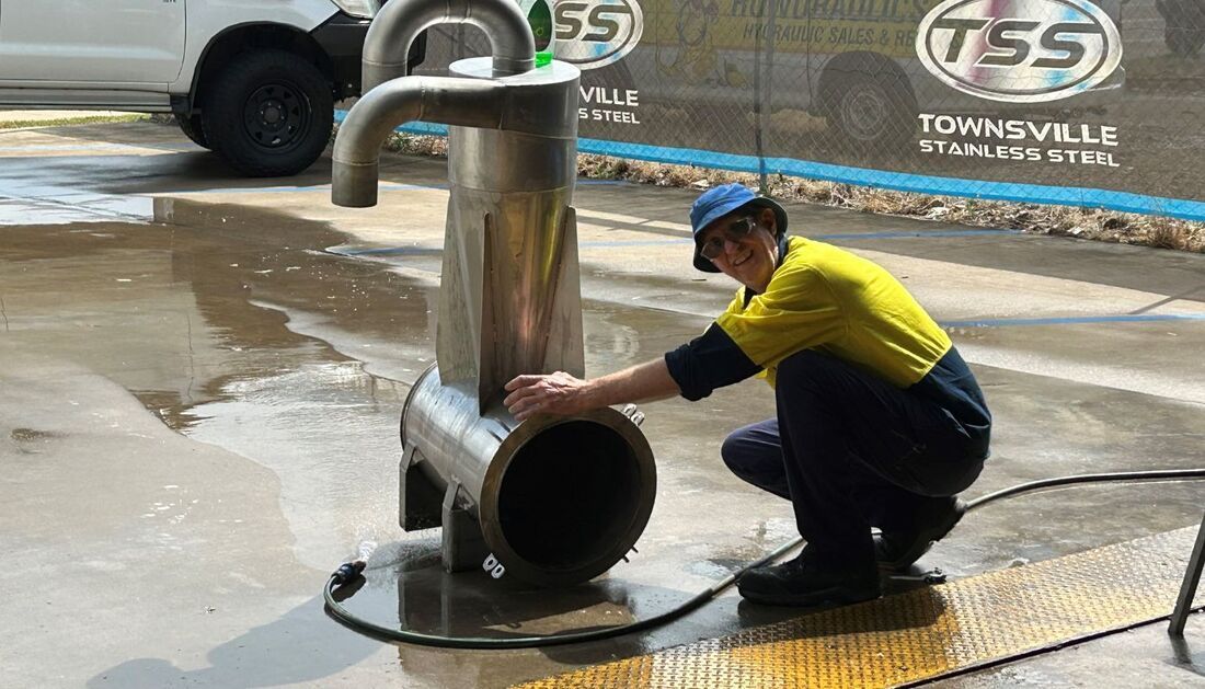 A Man Is Kneeling Down Next to A Large Metal Pipe — Townsville Stainless Steel in Garbutt, QLD