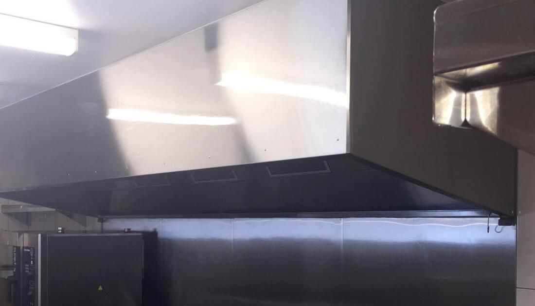 A Stainless Steel Hood Is Hanging from The Ceiling in A Kitchen — Townsville Stainless Steel in Garbutt, QLD