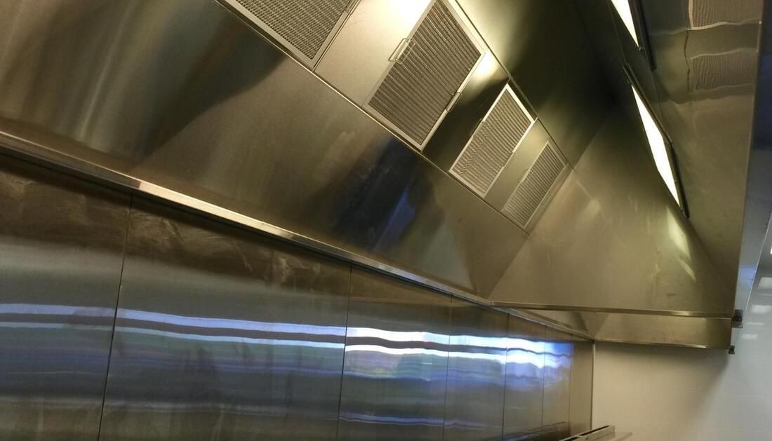A Stainless Steel Hood Is Hanging from The Ceiling of A Kitchen — Townsville Stainless Steel in Garbutt, QLD