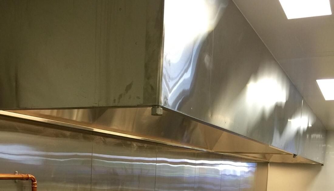 A Stainless Steel Hood Is Hanging from The Ceiling in A Kitchen — Townsville Stainless Steel in Garbutt, QLD