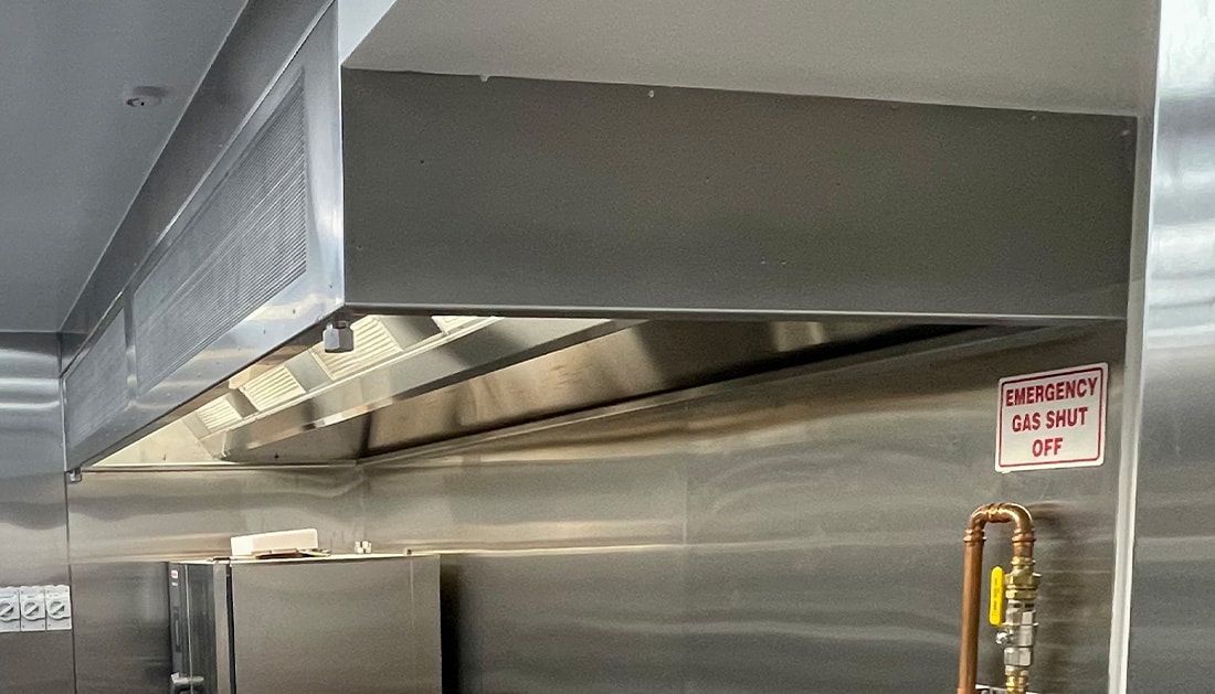 A Stainless Steel Hood Is Hanging from The Ceiling in A Kitchen — Townsville Stainless Steel in Garbutt, QLD