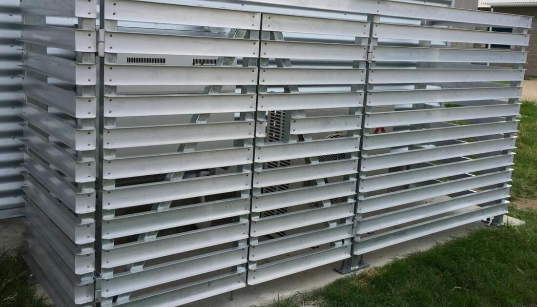 A Metal Fence Is Sitting in The Grass Next to A Building — Townsville Stainless Steel in Garbutt, QLD