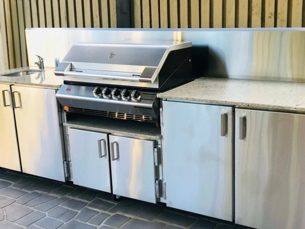 Outdoor stainless steel kitchen with grill, sink, and cabinets on a patio.— Townsville Stainless Steel in Garbutt, QLD
