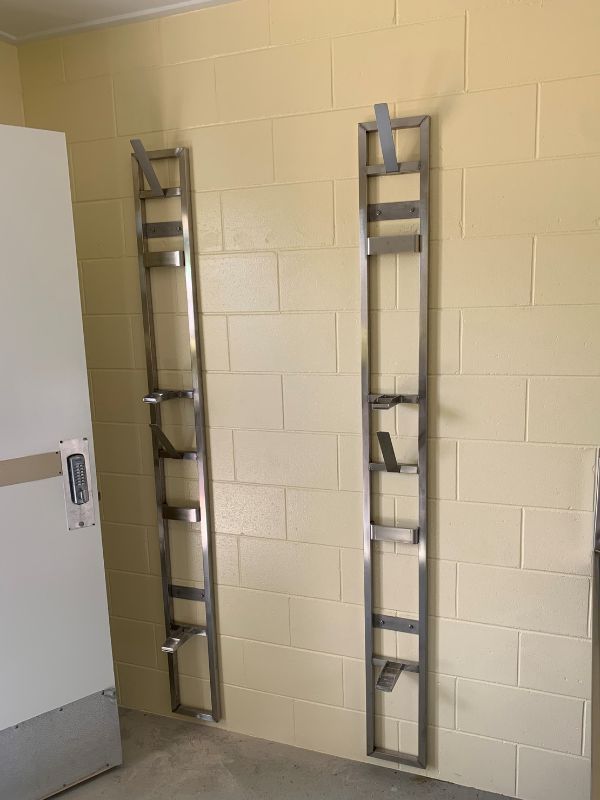 Two Metal Ladders Are Hanging on A Yellow Brick Wall  — Townsville Stainless Steel in Garbutt, QLD