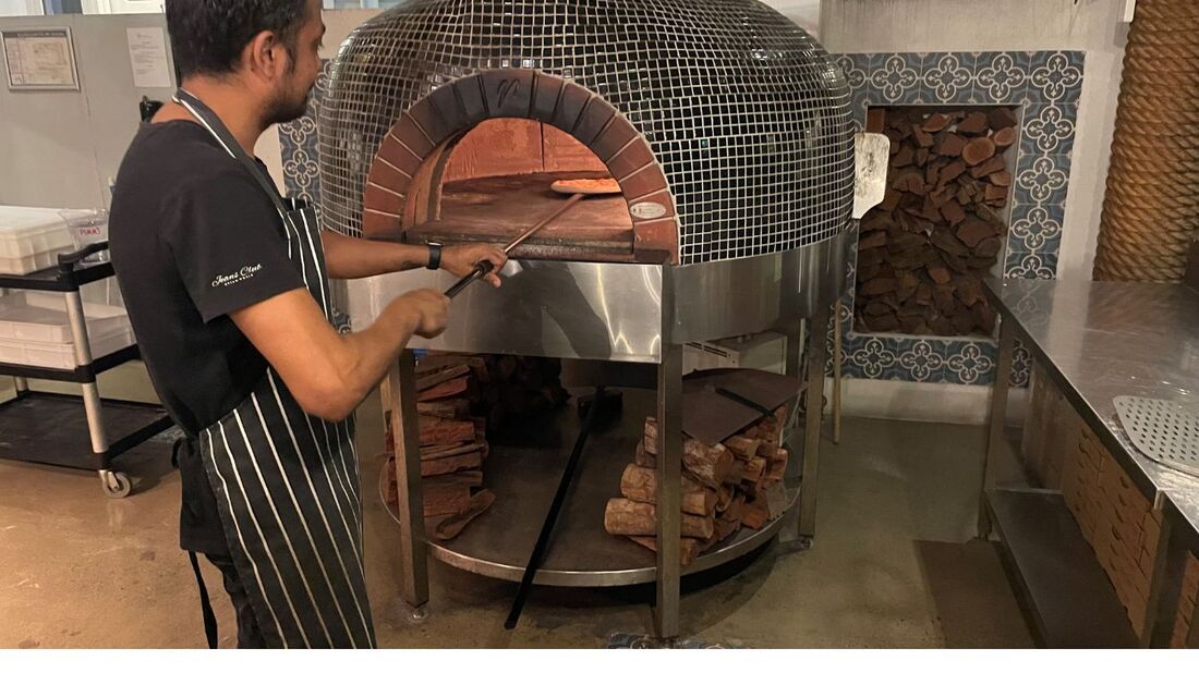 A Man Is Standing in Front of A Pizza Oven in A Kitchen  — Townsville Stainless Steel in Garbutt, QLD