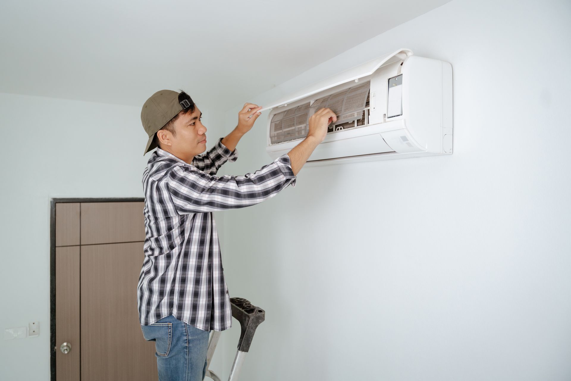 HVAC technician inspecting the filter of an AC, highlighting residential AC repair service. HVAC technician inspecting the filter of an AC, highlighting residential AC repair service.