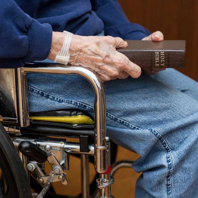 A man in a wheelchair is holding a holy Bible