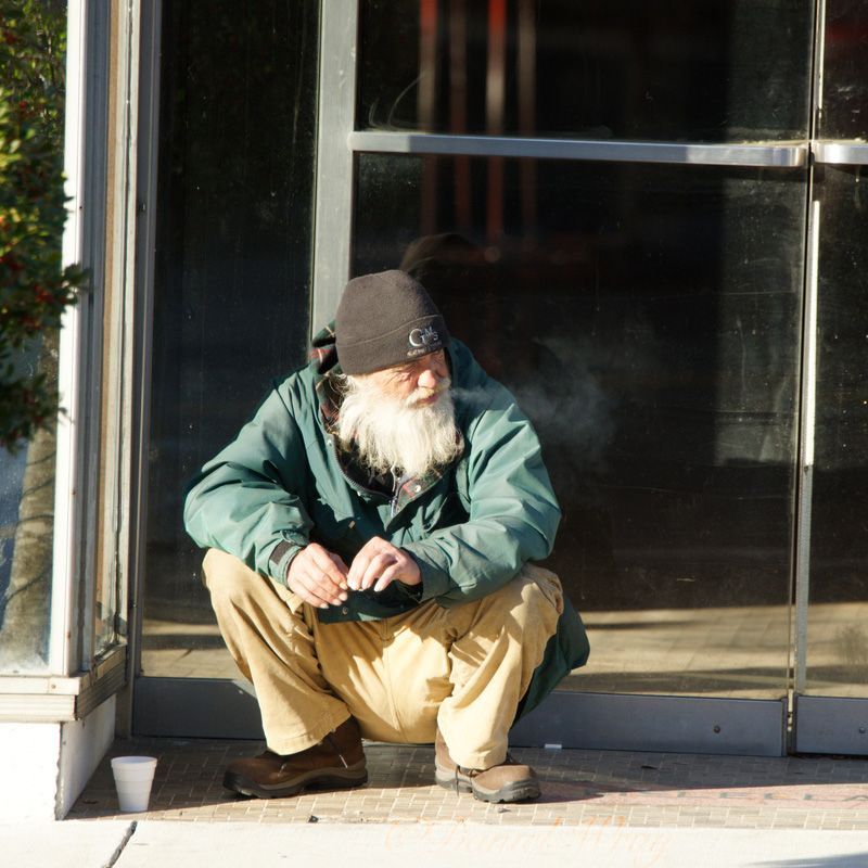 A man with a beard is squatting in front of a glass door
