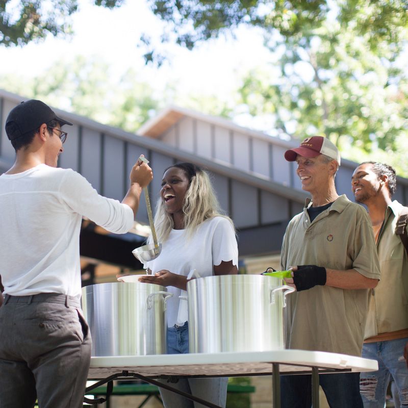A group of people standing around a table with pots on it