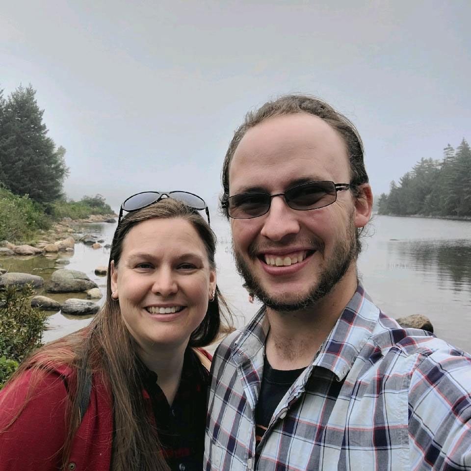 Pastor & Mrs. Michael Wareig are posing for a picture in front of a body of water.