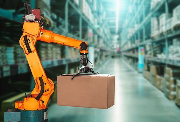 An autonomous robot arm in a vast warehouse, holding an unmarked cardboard box.