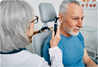 A doctor is examining a man 's ear with an otoscope.