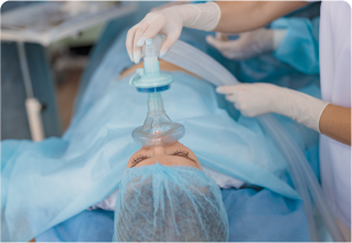 A woman in an operating room with an oxygen mask on her head