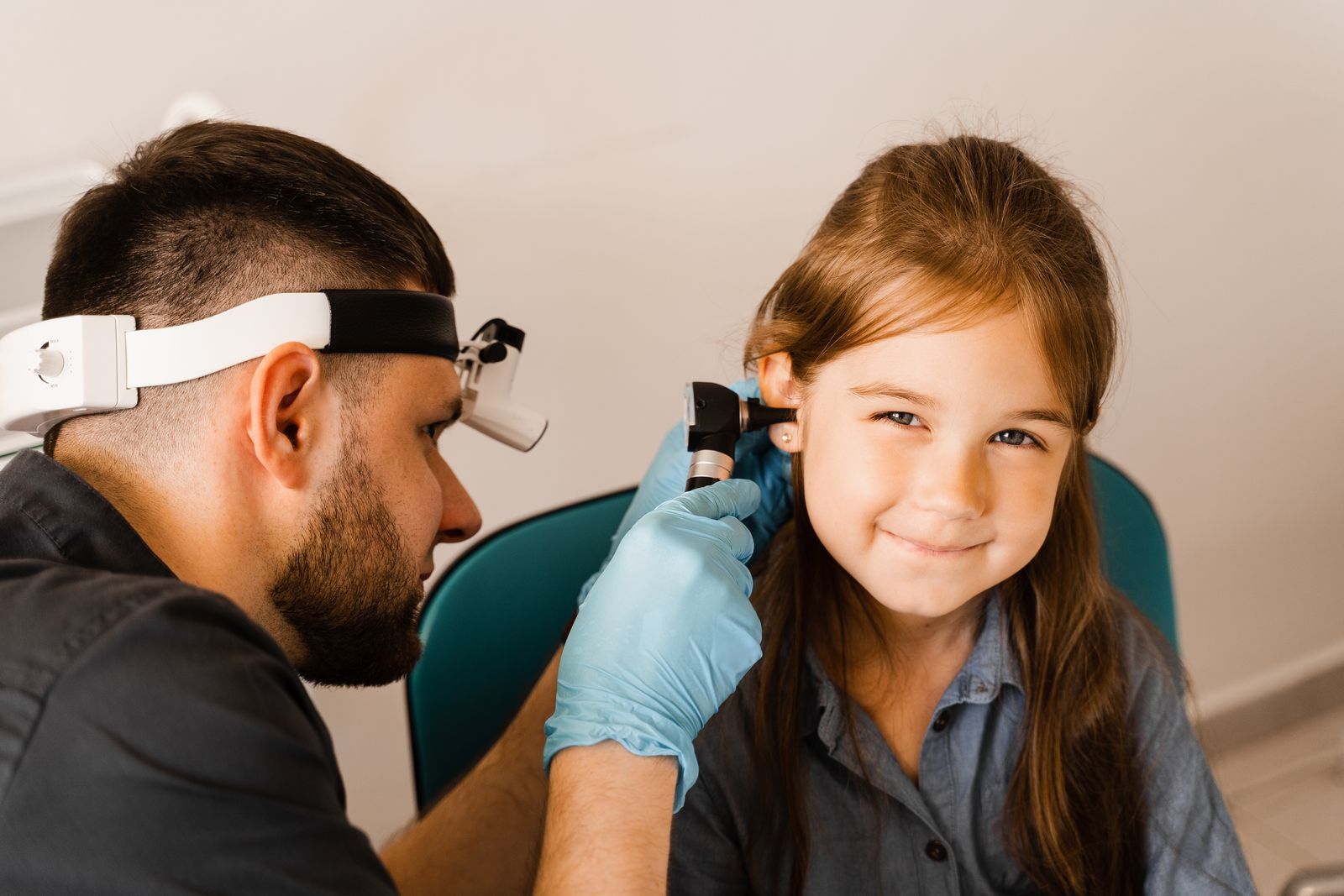 A little girl is getting her ears examined by a doctor.