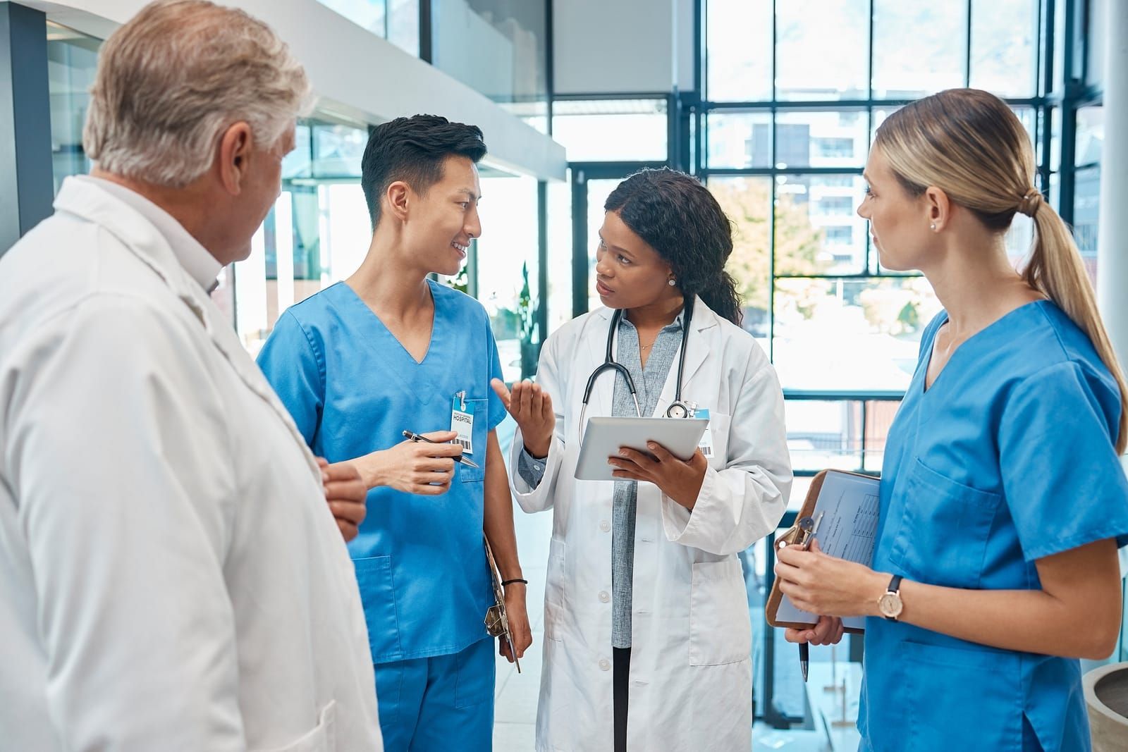 A group of doctors and nurses are talking to each other in a hospital hallway.