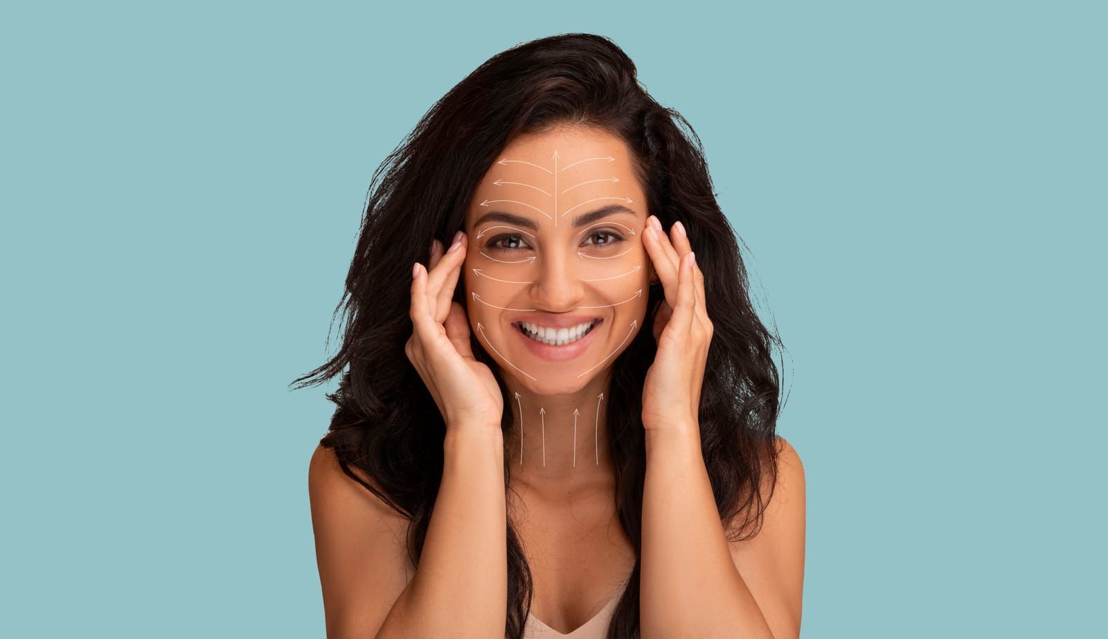 A woman is smiling and touching her face with her hands.