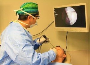 A surgeon is examining a patient 's mouth with a scope
