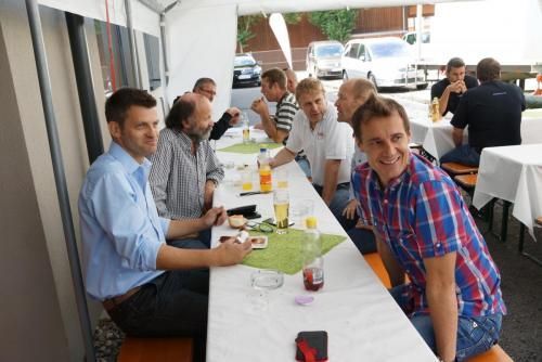 Eine Gruppe Männer sitzt an einem langen Tisch unter einem Zelt.