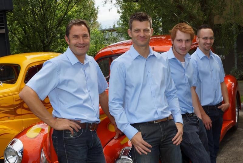 Eine Gruppe von Männern steht vor einem gelben und roten Auto