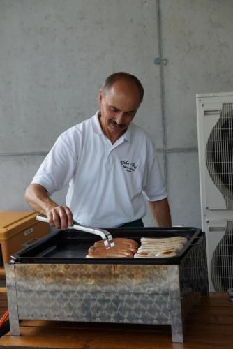 Ein Mann in einem weißen Hemd bereitet Essen auf einem Grill zu.
