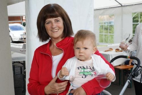 Eine Frau in einer roten Jacke hält ein Baby in ihren Armen.