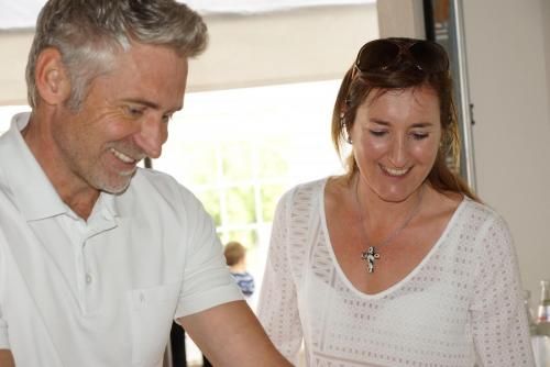 Ein Mann und eine Frau stehen nebeneinander und lächeln. Die Frau trägt eine Halskette mit einem Kreuz.